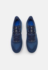 Un paio di scarpe da corsa Nike blu con suole bianche e lacci blu navy, viste dall'alto su uno sfondo bianco.