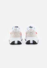 Białe buty sportowe z pomarańczowymi akcentami, szarym siateczkowym wykończeniem i beżowym wsparciem pięty. Czarna gumowa podeszwa z wyraźnym wzorem bieżnika.