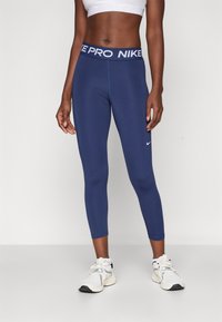 Námornícke modré legíny so širokým elastickým pásom s textom "NIKE PRO". Vyrobené z hladkej, elastickej látky pre pohodlie a dobré padnutie.