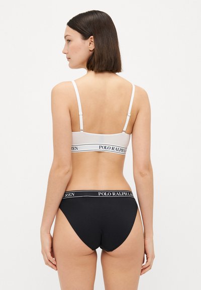 Hvit bralette med justerbare stropper og svart band merket "POLO RALPH LAUREN," kombinert med svart hipsterundertøy med matchende logoband.