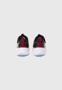 Une paire de baskets de sport noires et rouges vues de l'arrière, montrant des semelles blanches et des détails de semelle bleu clair sur fond blanc.