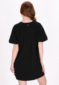 Rochie din bumbac neagră cu mâneci scurte puffate, decolteu rotund și un mic detaliu cu logo în spate. Textură netedă, design până la genunchi.