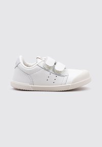 Zapatilla de cuero blanca con dos correas de Velcro, acentos grises en el talón, suela de goma texturizada y detalles perforados.