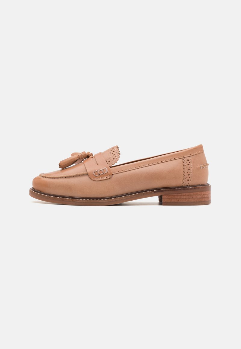 Light tan leather loafers with a rounded toe, decorative tassels, perforated accents, and a low wooden heel. Smooth texture overall.