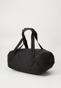 Borsone nero realizzato in tessuto resistente, dotato di doppi manici, chiusura con zip e base arrotondata per la stabilità.