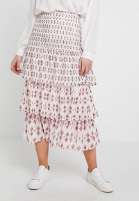 Ker skirt midi bertingkat dari kain ringan, menampilkan latar belakang putih dengan pola berlian merah. Dilengkapi dengan lapisan berenda.