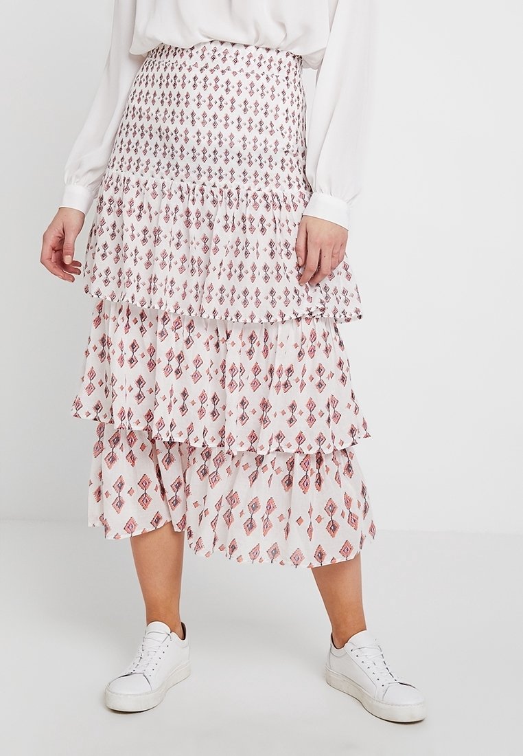 Ker skirt midi bertingkat dari kain ringan, menampilkan latar belakang putih dengan pola berlian merah. Dilengkapi dengan lapisan berenda.