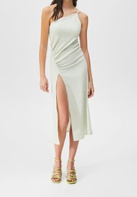 Grünes kariertes Maxikleid mit einem schulterfreien Design, drapiertem Stoff und seitlichem Schlitz. Kombiniert mit limegrünen Sandalen mit Riemchen.