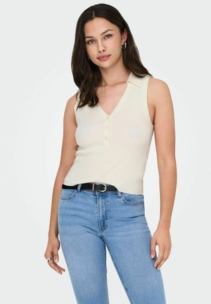 Top sans manches côtelé crème avec un col en V et une patte de boutonnage, associé à un jean taille haute bleu clair et une ceinture noire.