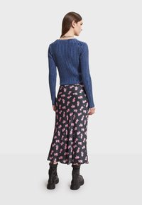 Tmavě modrý žebrovaný svetr s dlouhými rukávy, v kombinaci s černou sukní s růžovým květinovým potiskem, doplněno černými bojovými botami.