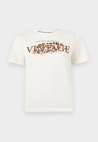 Λευκό κοντομάνικο μπλουζάκι με το κείμενο «MAKE YOUR DREAMS REAL VINTAGE» πάνω σε ροζ και λεοπάρ σχέδιο στο στήθος.