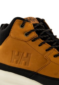 Sneaker in camoscio marrone con accenti in rete nera, lacci neri rotondi e occhielli in metallo. Logo "HH" impressa sul lato. Suola in gomma bianca.