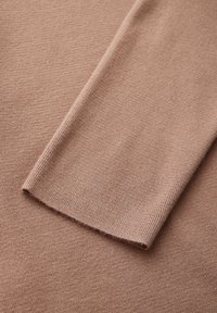 Stickad tröja i en mjuk, dammig rosafärg med en jämn textur. Har långa ärmar och ribbade muddar för en figurnära passform.