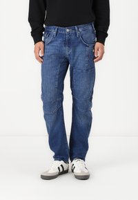 Denim jeans in dark blue with a straight-leg cut, multi-pocket design, contrast stitching, and a classic five-pocket layout.