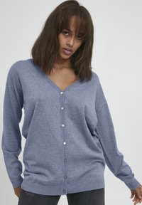 Cardigan azzurro chiaro in morbido tessuto a maglia, con scollatura a V, maniche lunghe e chiusura frontale con bottoni con accenti in argento.