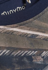 Bomulds t-shirt med camo mønster i nuancer af grønt og brunt. Marineblå ribbet halsudskæring med syet sømdetalje. Brandlogo synligt.