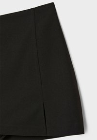 Sort nederdel med en glat, tekstureret stof. Har en let plissering ved kanten og en sideslids, der skaber et rent, skræddersyet udseende.