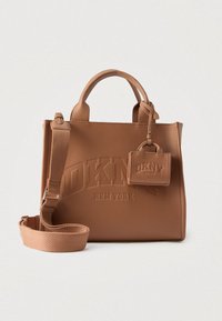 Sac à main en cuir marron DKNY avec poign�ées supérieures, bandoulière réglable et petite pochette assortie attachée sur fond uni.