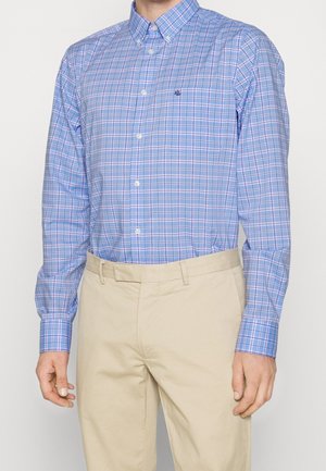 Niebiesko-biała, kraciasta koszula z długim rękawem i guzikami, połączona z beżowymi spodniami, noszona przez osobę stojącą na jednolitym tle.