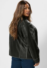 Giacca di pelle nera con un design pulito e su misura. Presenta cuciture contrastanti, un colletto strutturato e una vestibilità rilassata, vista da dietro.