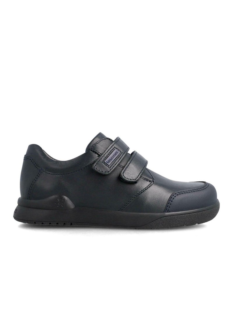 Zapatillas de velcro negras con parte superior de cuero suave, punta redondeada, cuello acolchado y suela de goma texturizada. Diseño minimalista sin patrones.