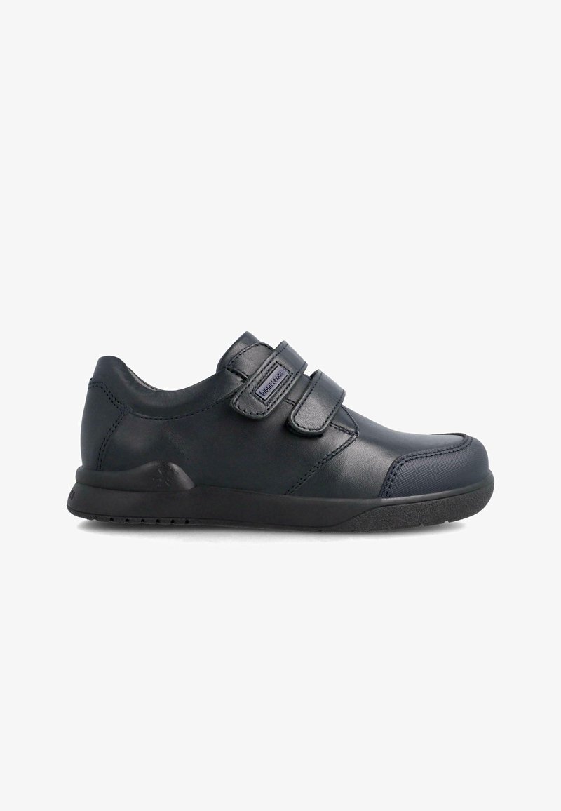 Zapatillas de velcro negras con parte superior de cuero suave, punta redondeada, cuello acolchado y suela de goma texturizada. Diseño minimalista sin patrones.