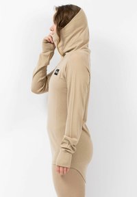 Beige lange mouw hoodie met een ritssluiting aan de voorkant en hoge kraag, met een geribbelde textuur en een logo patch op de borst.