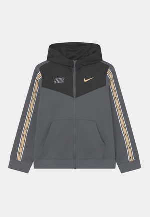 Gray zip-up hoodie features a black hood, Nike logos, and gold accents on the shoulders. Made from soft, textured fabric with front pockets.