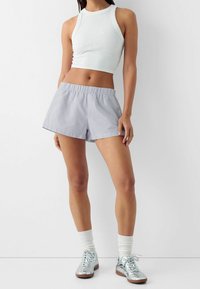 Randiga bomullsshorts med resår i midjan och en avslappnad passform. Matchas med en vit crop top och silvriga metallic sneakers.