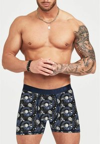 Boxer da uomo in tema spaziale con un motivo blu navy e nero, caratterizzati da pianeti e stelle, cintura elastica e vestibilità aderente.