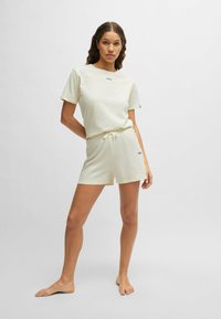 Ljusgrön loungewear-set som består av en t-shirt med kort ärm och en svart logotyp samt shorts med dragsko, båda i mjukt och lätt material.