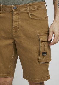 Smeđe cargo kratke hlače od twill tkanine, s bočnom džepom, prošivenim detaljima i zatvaranjem na dugme u području struka.