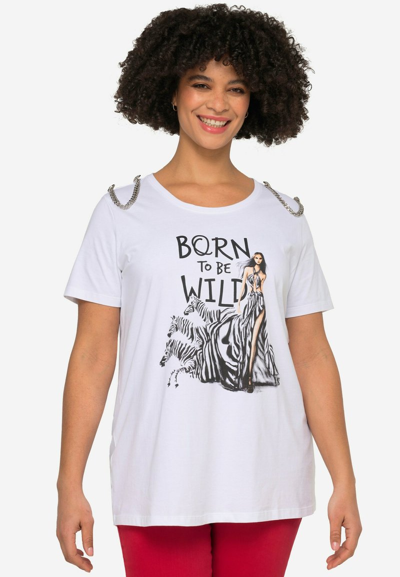 Hvid t-shirt med korte ærmer, prydet med et grafisk design af en catwalk-model og zebraer, sølvfarvede skulderdetaljer og fed tekst, der siger "BORN TO BE WILD."