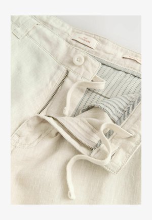 Svetlo béžové ľanové šortky so zipsom a gombíkovým zapínaním, s pruhovanou vnútornou podšívkou a šnúrkou, predvádzajúce jemnú, textúrovanú látku.
