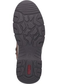 Suela de zapato de goma negra con surcos profundos, que presenta patrones diversos y una ligera curva en el talón. Logo central en rojo: "rieker."