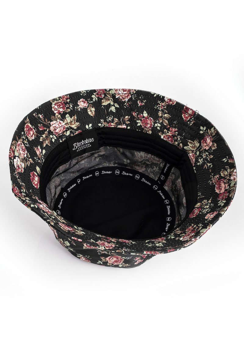 Cappello a secchiello con motivo floreale su sfondo nero, caratterizzato da rose rosa e foglie verdi. L'interno è in tessuto nero con branding.