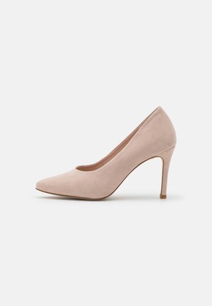 Różowe zamszowe szpilki w kolorze nude z zaostrzonym noskiem, gładką teksturą i smukłym obcasem typu sztylet. Minimalistyczny design z elegancką sylwetką.