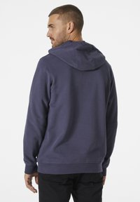 Sudadera con capucha azul marino con cordón, puños y dobladillo acanalados. Fabricada de una mezcla de algodón con una textura suave. Diseño liso.