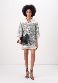 Rochie cu mânecă scurtă, cu un fond deschis, model floral verde și negru, decolteu în V, cu detalii contrastante, asortată cu o plic negru și sandale cu bretele.