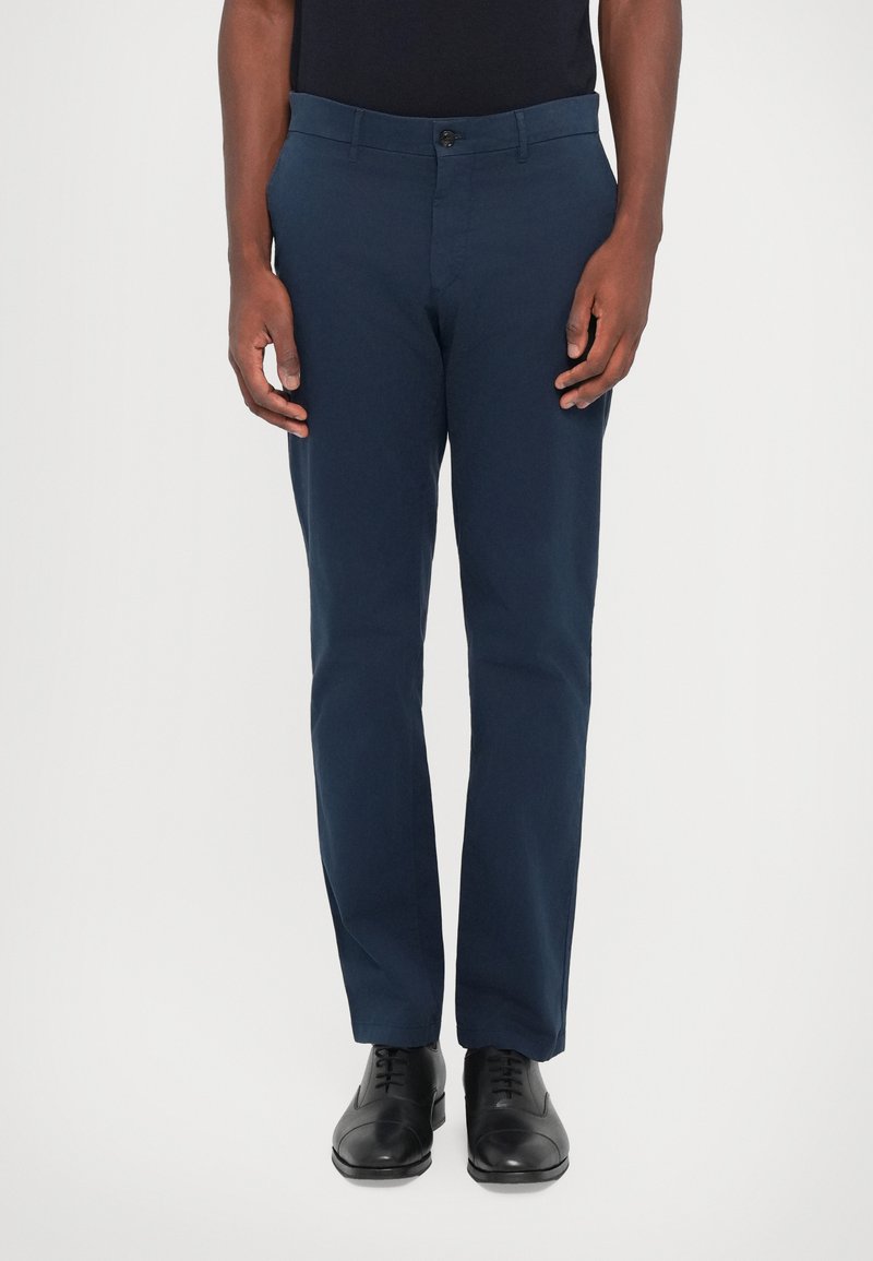 Navy blue trousers made of smooth fabric, featuring a button closure, front pockets, and tailored design. Worn with black dress shoes.