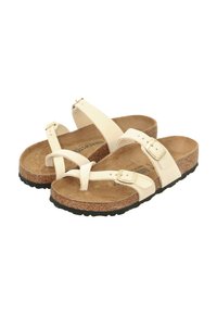 Sandali in pelle beige con due fibbie regolabili, plantare in sughero e suola in gomma nera testurizzata. Presentano un design minimalista e un anello per l'alluce.