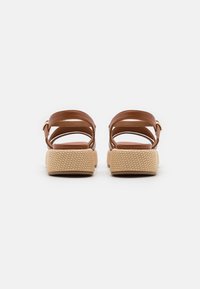 Bruine leren sandalen met twee verstelbare banden, een textuur die doet denken aan jute voor de zool en een glad voetbed. Minimalistisch ontwerp en neutrale kleur.
