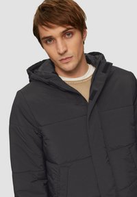 Schwarze Puffjacke mit Kapuze, ausgestattet mit einem Reißverschluss vorne, Klettverschlussakzenten und gesteppten Panels; weiche Textur, praktisches Design.
