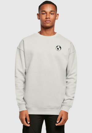 Lys grå sweatshirt med et rundt sort globuslogo på venstre bryst. Har lange ærmer og en ribbet halsudskæring og kant.