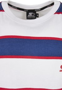 Tricou cu mânecă scurtă, de culoare albă, cu dungi orizontale late în albastru și roșu. Are gât rotund și un logo roșu în partea dreaptă jos.