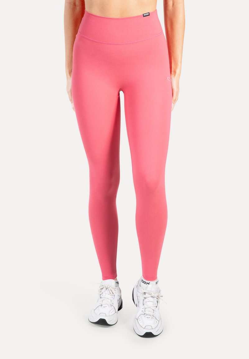 Roze legging met hoge taille gemaakt van rekbaar materiaal, nauwsluitend ontwerp, gladde textuur, gecombineerd met witte sportschoenen.