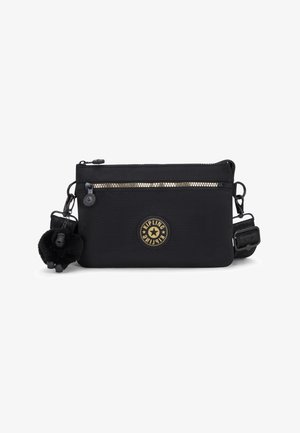 Schwarze Stoff-Crossbody-Tasche mit einem goldenen Reißverschluss, runder Logo-Patch und einem weichen schwarzen Schlüsselanhänger. Mit einem verstellbaren Tragegurt.