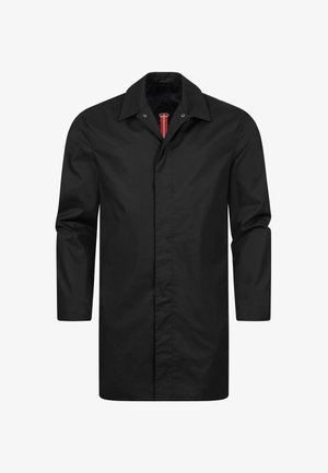 Fekete, hosszú kabát sima anyagból, hegyes gallérral, gombos záródással és egyetlen piros díszítéssel a nyakrésznél.