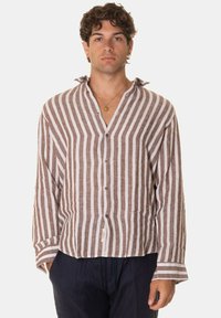 Camicia di lino a strisce marroni e bianche con maniche lunghe, scollo a v e bottoni sul davanti. Vestibilità rilassata con orlo curvo.