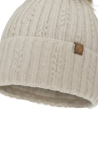 Bonnet tricoté en ivoire avec une texture côtelée, un revers plié et une petite étiquette brune ornée d'un motif de feuille. Sommet orné d'un pompon en fausse fourrure.